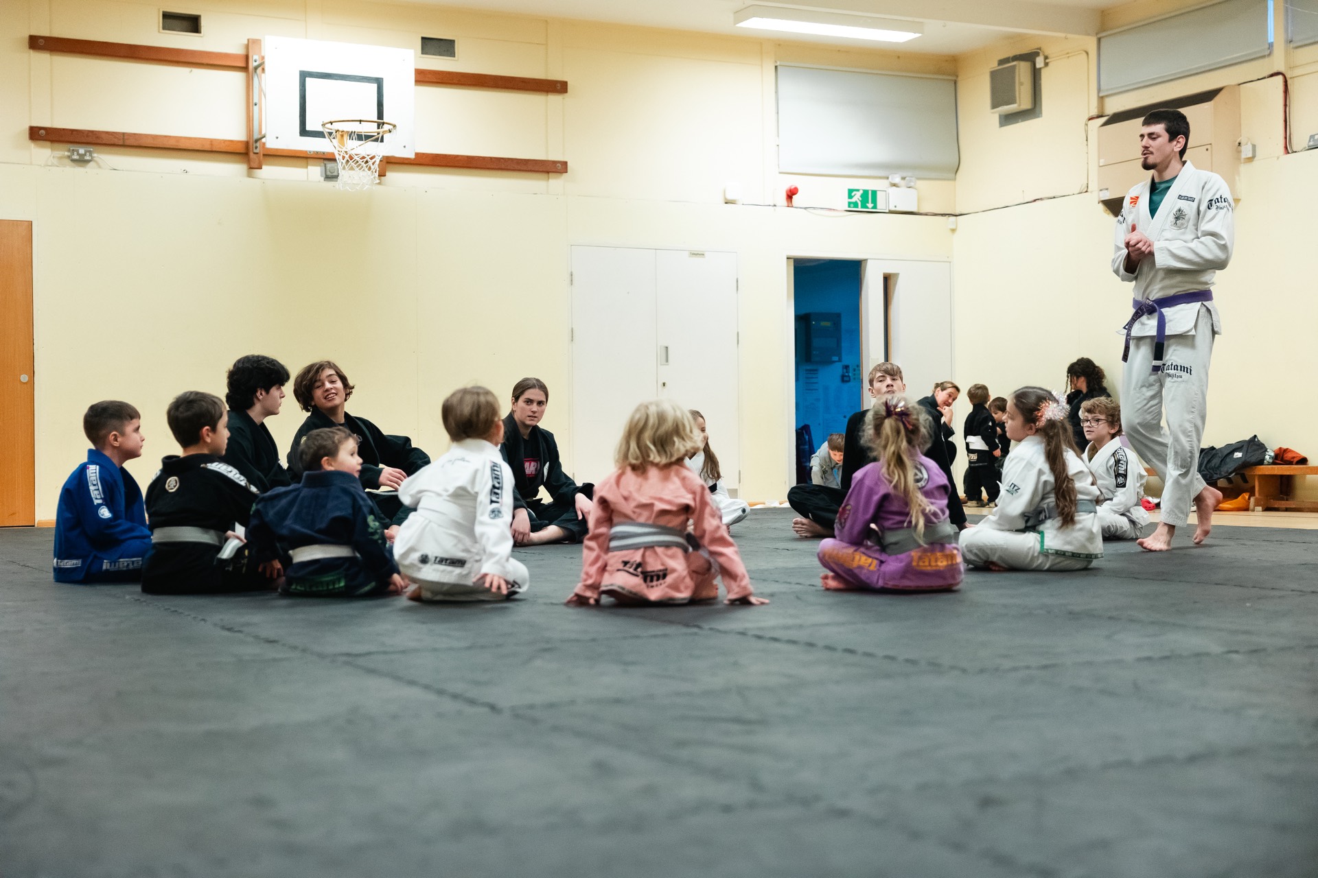 A Grow coach leading a circle of children in a school hall