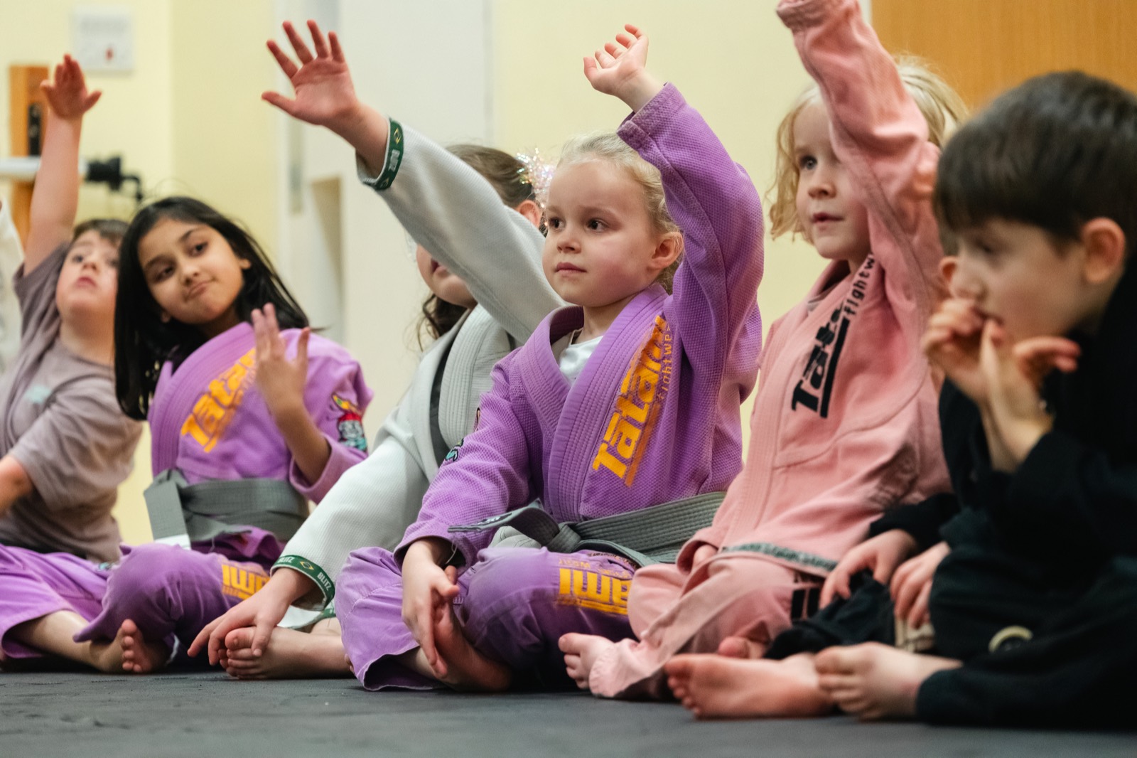 Engaged children with their hands raised in a Grow class
